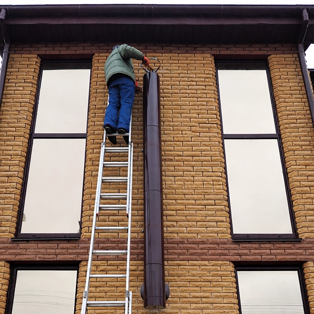 Майстер виконує монтаж димаря у приватному будинку